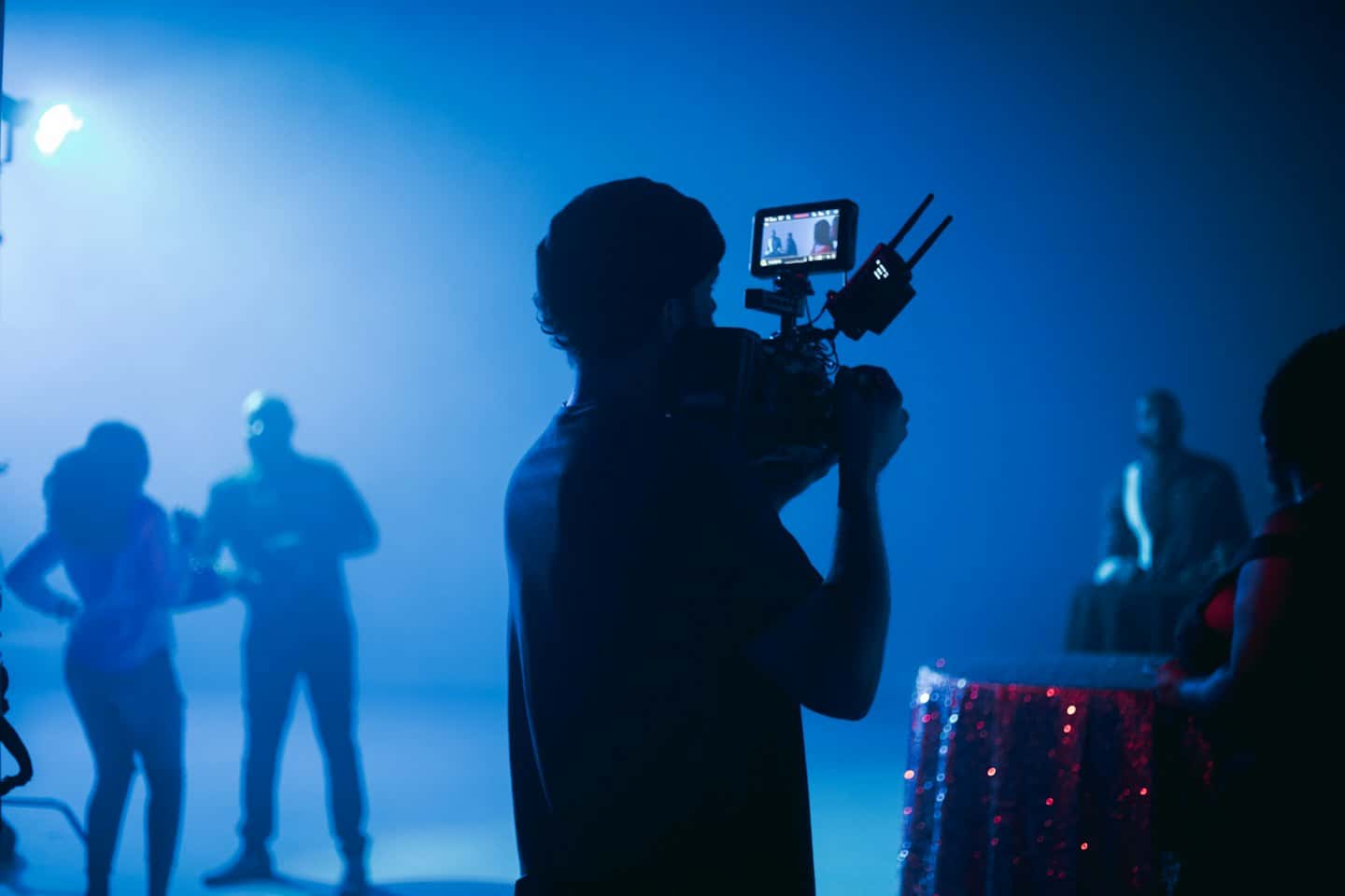 Un videografo riprende figure in silhouette in uno studio.